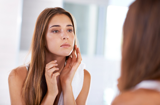 Young woman concerned looking in the mirror