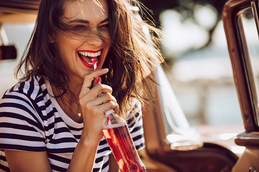 Woman drinking pop from a straw and smiling