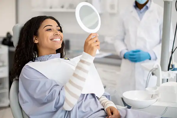 Young woman smiling in dentist chair with a mirror after her dental exam