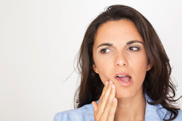 Woman holding cheek due to tooth ache