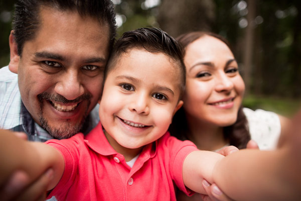 Young boy smiling while taking a selfie photo with his parents