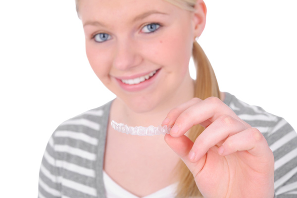 Teenage girl holding her clear aligner