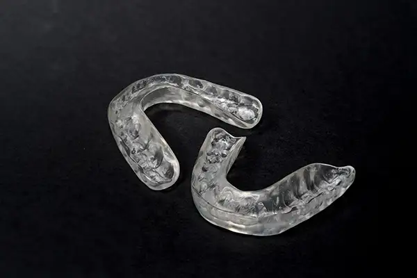 Pair of clear mouth guards placed on a black background, commonly used for bruxism or teeth protection.